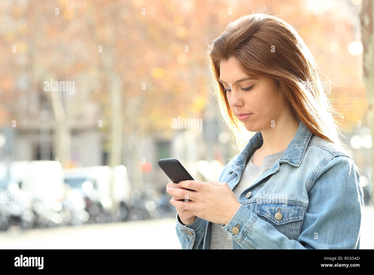 Ernsthafte Jugendmädchen plaudern auf Smart Phone zu Fuß auf der Straße Stockfoto