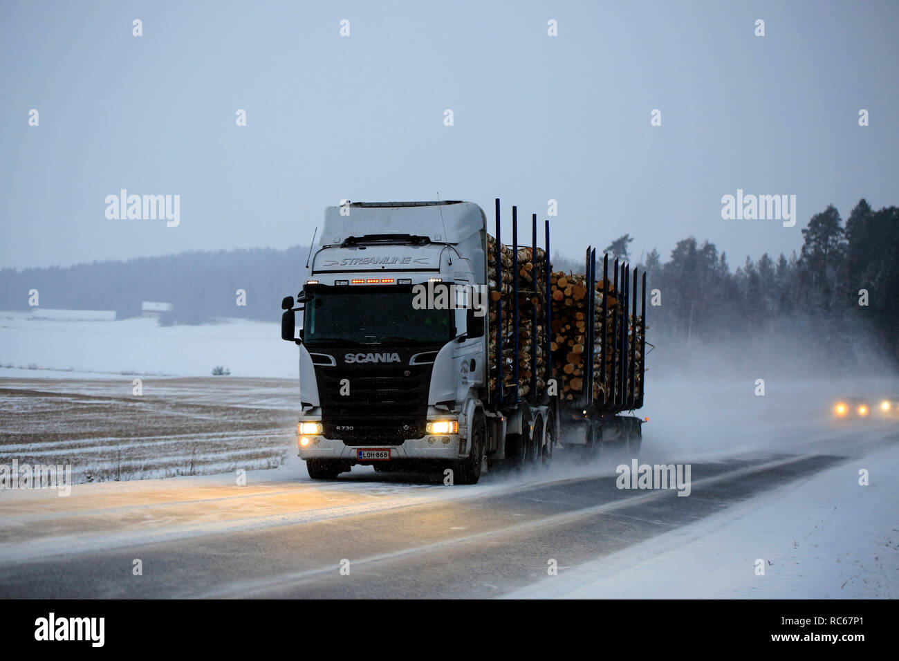 Salo, Finnland - Dezember 21, 2018: Silber Scania R730 Streamline logging Truck hols Last auf verschneiter Straße an einem Winterabend im Süden Finnlands. Stockfoto
