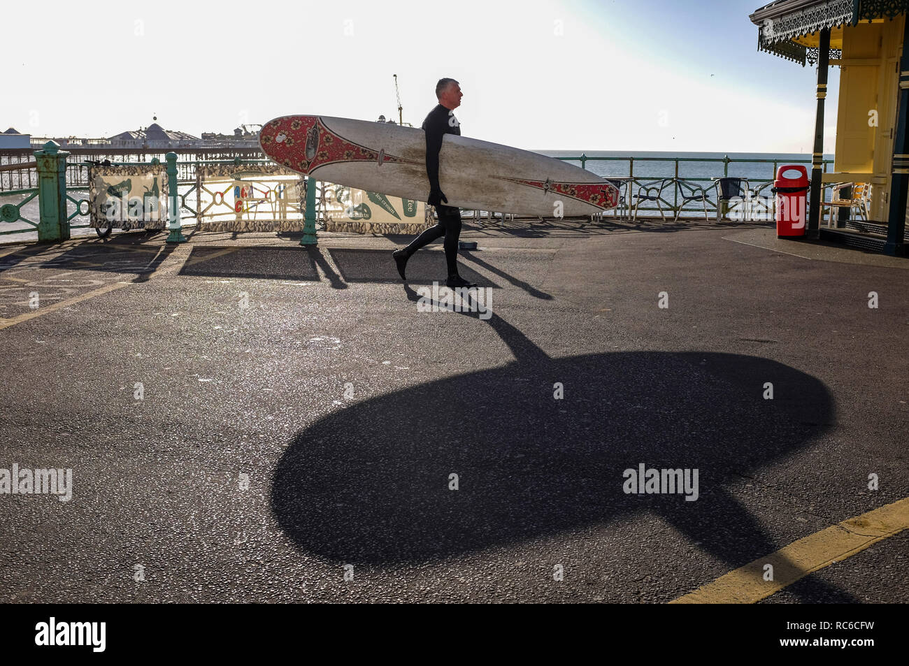 Brighton, UK. 14 Jan, 2019. Ein surfer Blätter Brighton Beach auf einer schönen sonnigen Morgen an der Südküste, aber kalten Wetter zu fegen über Großbritannien Prognose später diese Woche: Simon Dack/Alamy leben Nachrichten Stockfoto