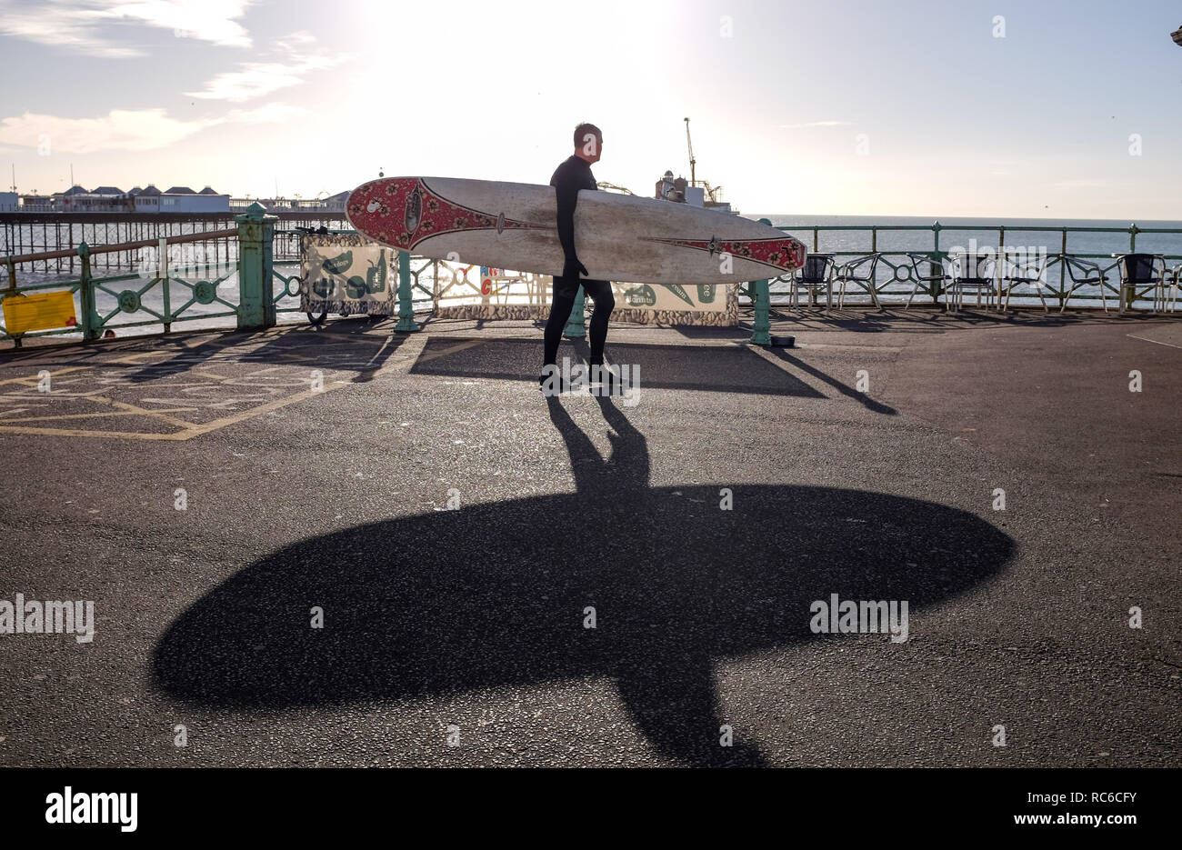 Brighton, UK. 14 Jan, 2019. Ein surfer Blätter Brighton Beach auf einer schönen sonnigen Morgen an der Südküste, aber kalten Wetter zu fegen über Großbritannien Prognose später diese Woche: Simon Dack/Alamy leben Nachrichten Stockfoto