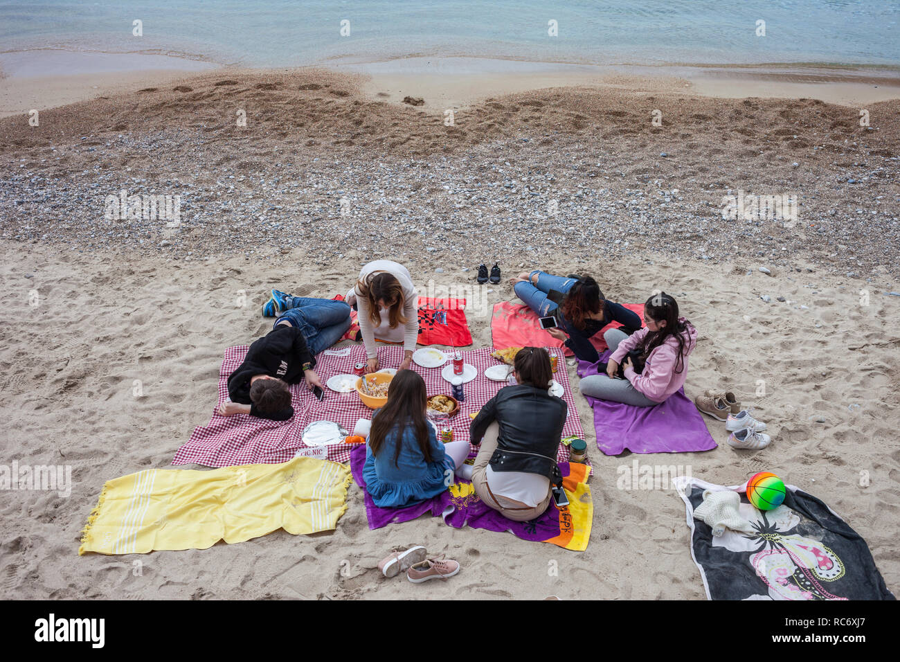 Gruppe von jungen Menschen mit Picknick an einem Strand in Villefranche-sur-Mer in Frankreich, Badeort am Mittelmeer auf dem französischen Riviera-Côte d'Azur Stockfoto