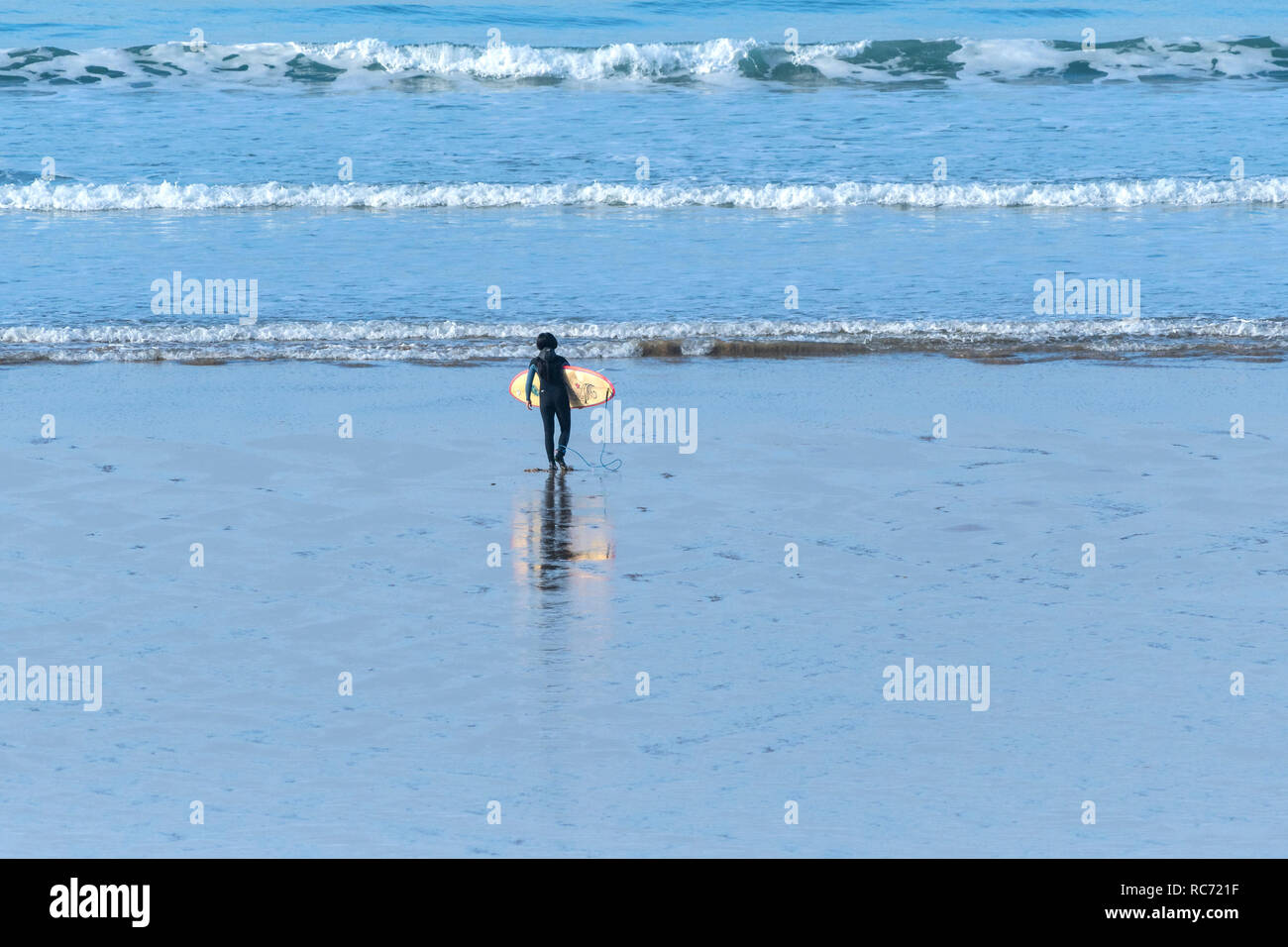 Ein einsamer Surfer mit einem Surfbrett zu Fuß das Meer in Cornwall. Stockfoto