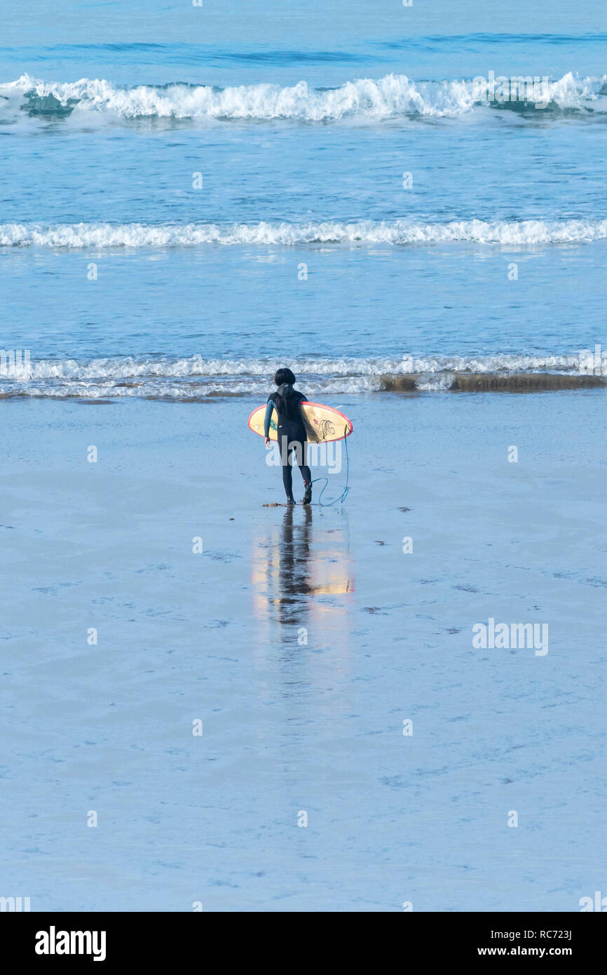 Ein einsamer Surfer mit einem Surfbrett und zu Fuß zum Meer. Stockfoto