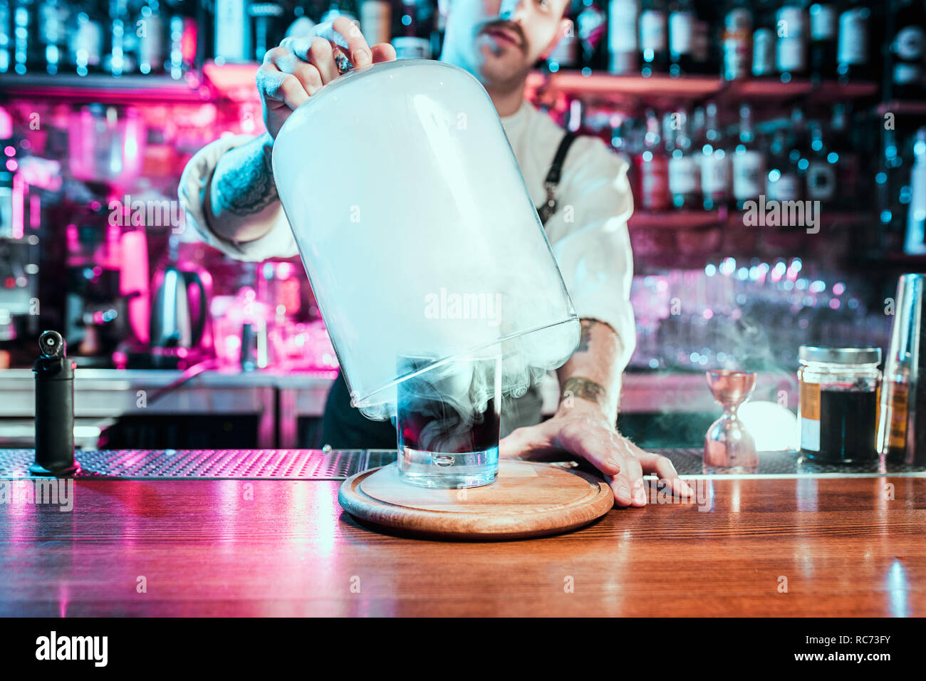 Experte Barkeeper macht Cocktail in der Nacht Club oder Bar. Glas feurigen Cocktail auf der Theke vor dem Hintergrund der Barkeeper Hände mit Feuer. Barkeeper tag Konzept Stockfoto