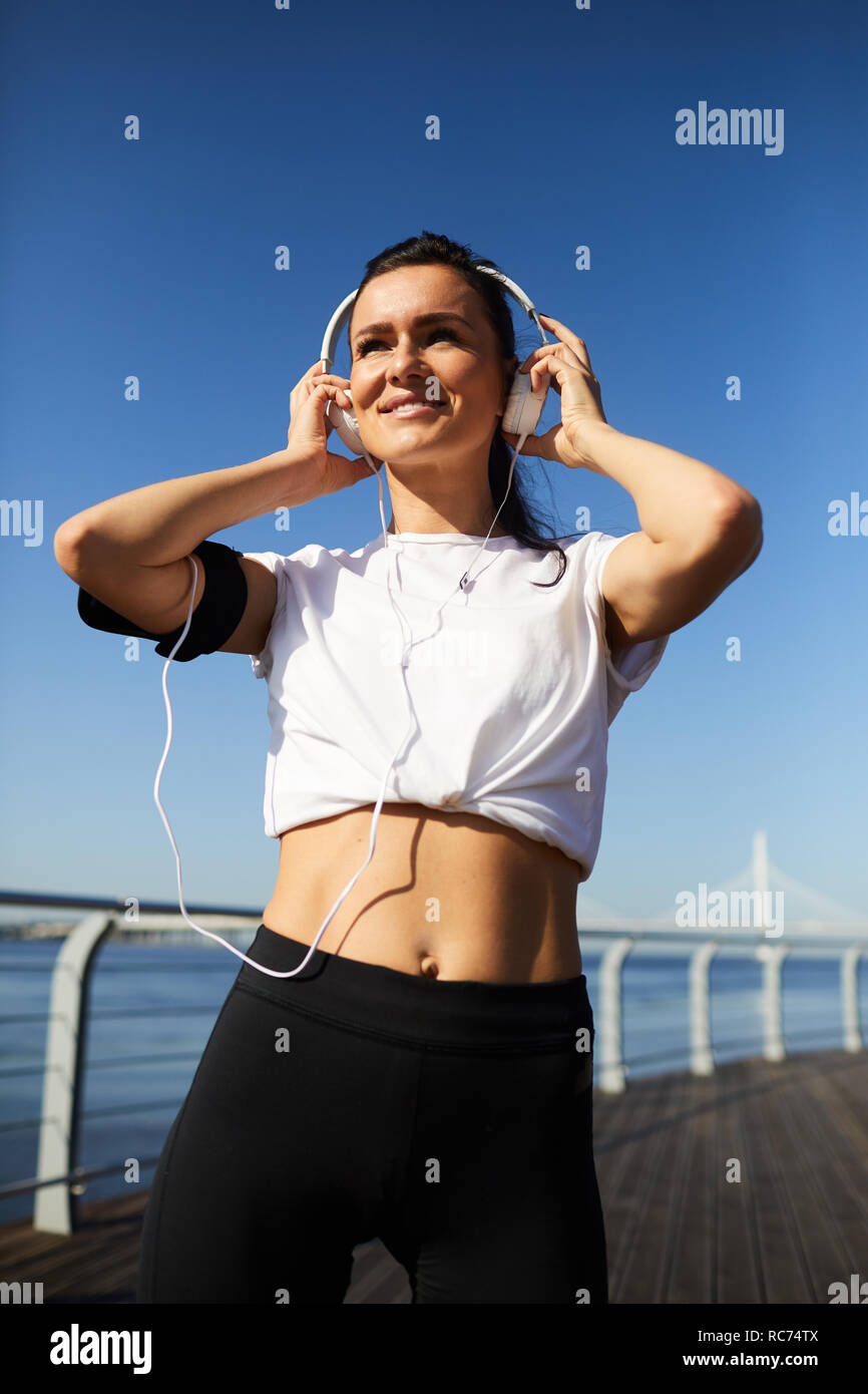 Glückliche Frau in Kopfhörer vorbereiten für Outdoor Training Stockfoto