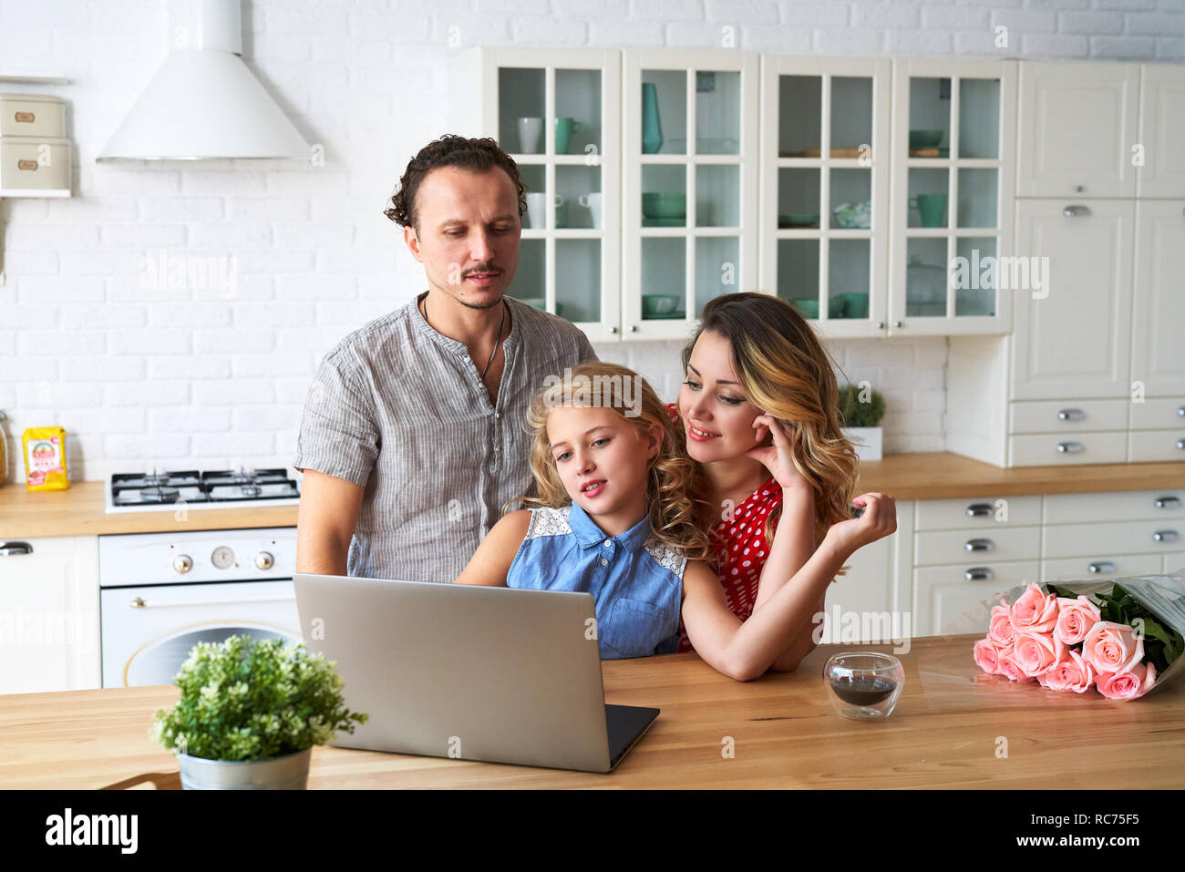 Junge, glückliche Familie im Internet surfen mit Laptop am Tisch in der Küche Stockfoto