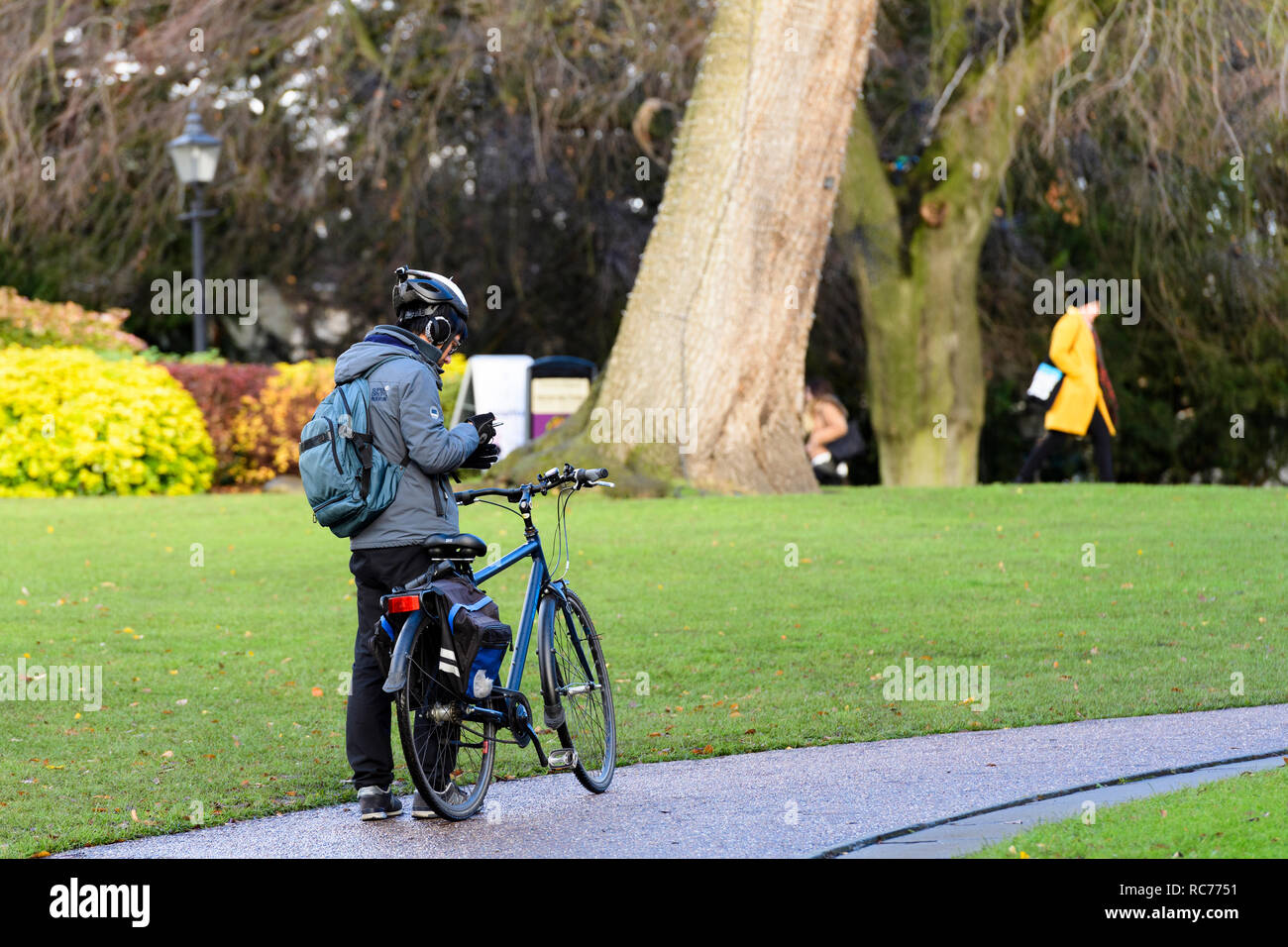 Männliche Radfahrer in Helm ist Gehorsam park Regeln & hat abmontiert, stehend mit Rad & Blick auf Telefon-Museum Gardens, York, Yorkshire, England, UK. Stockfoto