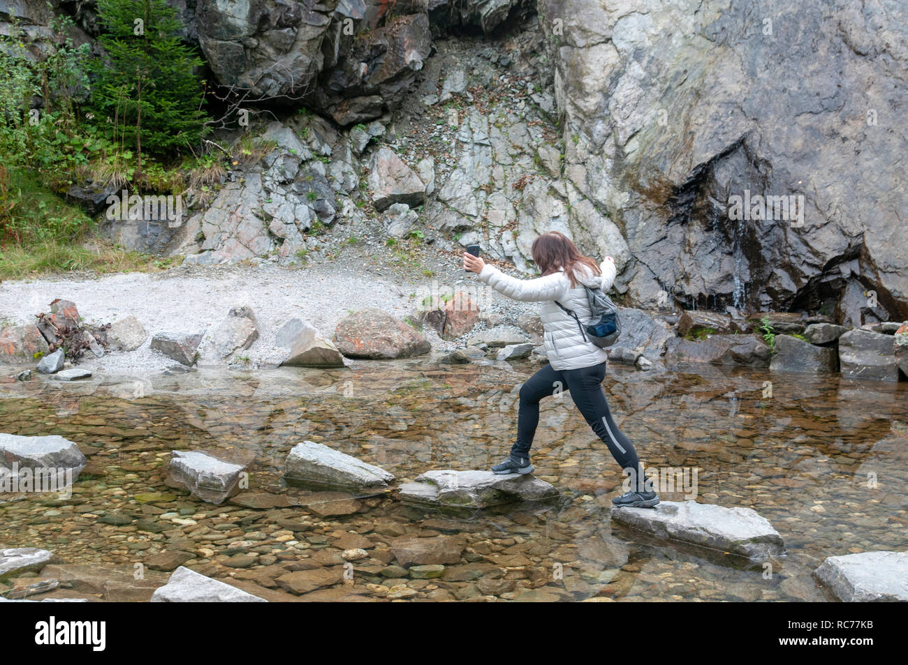 Frau überspringt Trittsteine in einem Teich gelegt. Auf der "Wilde Wasser Weg' Stubai, Tirol, Österreich fotografiert. Stockfoto