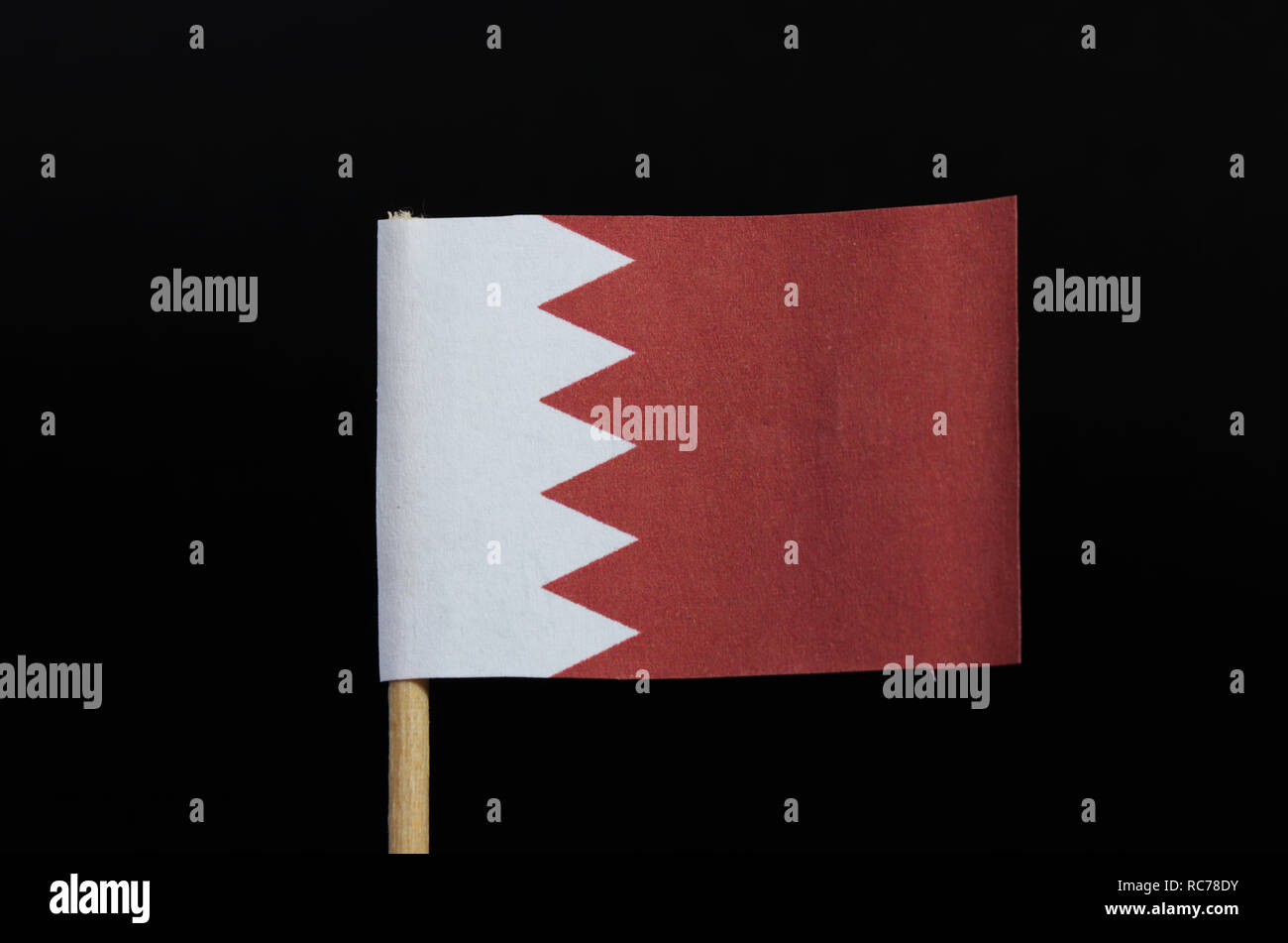 Eine nationale Flagge von Bahrain auf Zahnstocher auf schwarzem Hintergrund. Ein weißes Feld auf der Hoist Seite aus einer größeren roten Feld getrennt, indem fünf whit Stockfoto