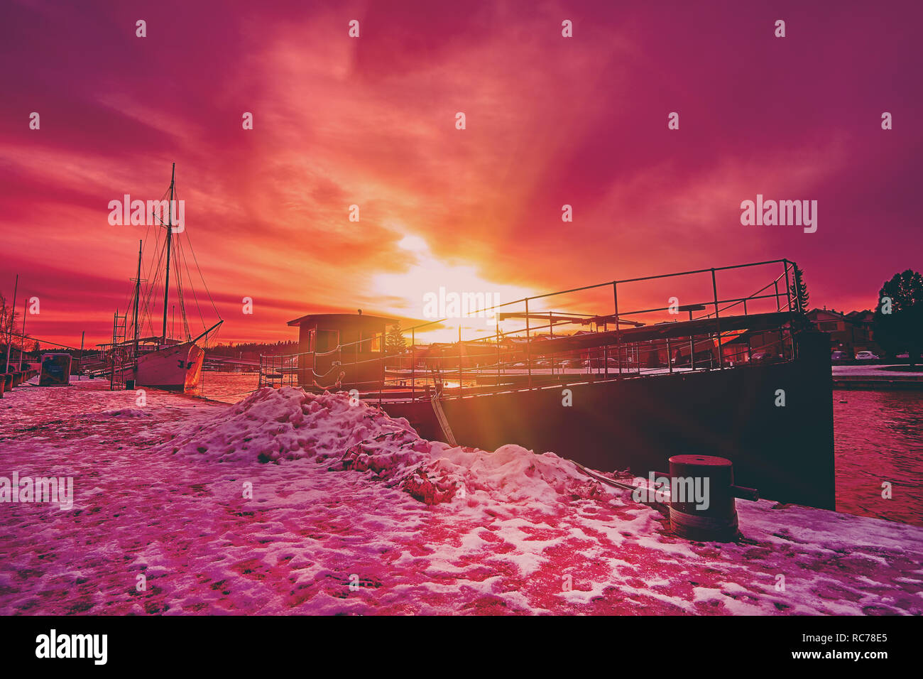 Malerische rot lila und violett Sonnenuntergang über Landschaft Fluss in Europa mit alten Schiffen Rest in den verschneiten Hafen Pier Stockfoto