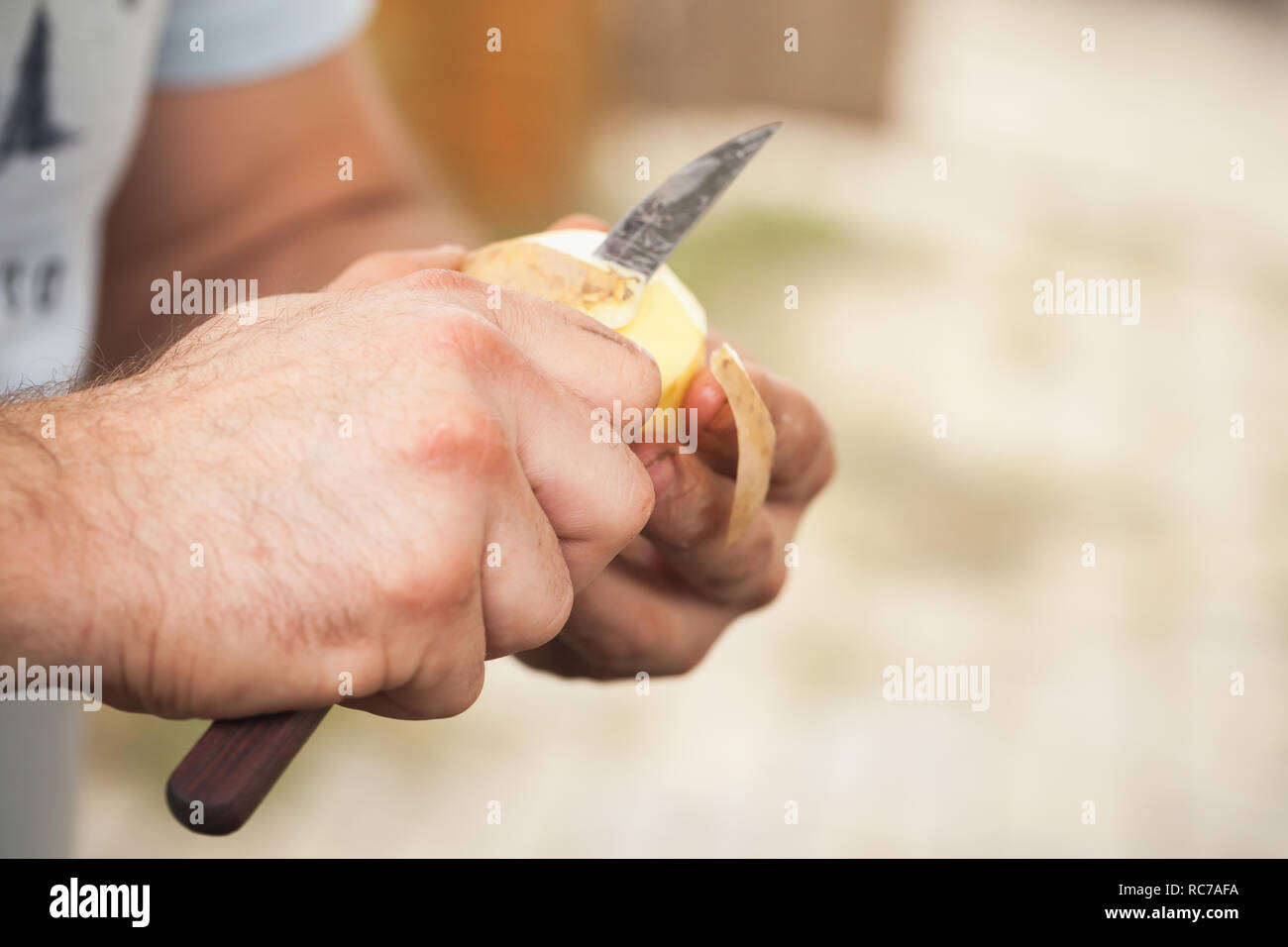 Rohe Kartoffel schälen, Hände von Cook mit Messer, Nahaufnahme mit selektiven Fokus Stockfoto