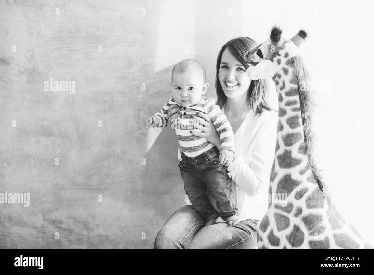 Mutter Holding baby Junge neben Spielzeug Giraffe Stockfoto