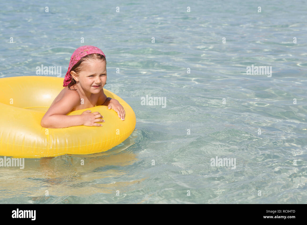 Mädchen spielen mit gelben Schlauchboot im Meer, San Vito lo Capo, Sizilien, Italien Stockfoto