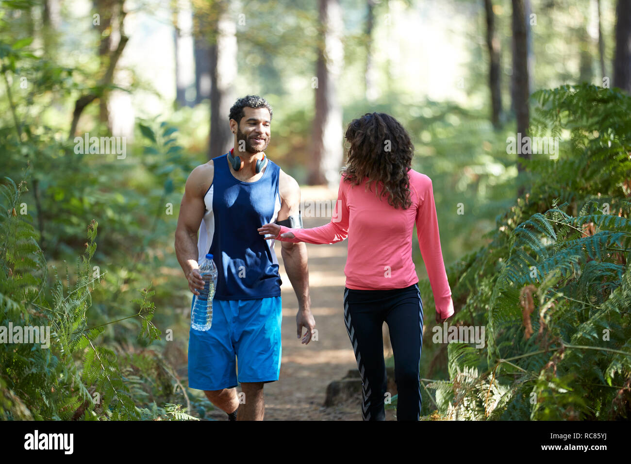 Männlichen und weiblichen Läufern teilen Mineralwasser im Wald Stockfoto