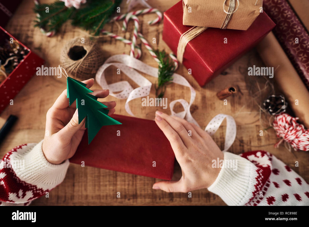 Frau anhängen Weihnachtsbaum geformte Dekoration auf Weihnachtsgeschenk Stockfoto