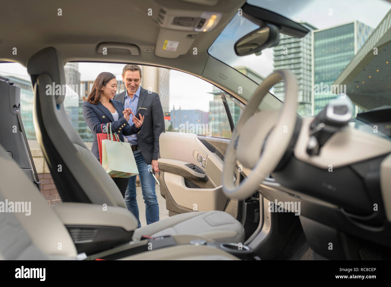 Mann und Frau Kontrolle Auto kostenlos auf Handy app, Manchester, UK Stockfoto