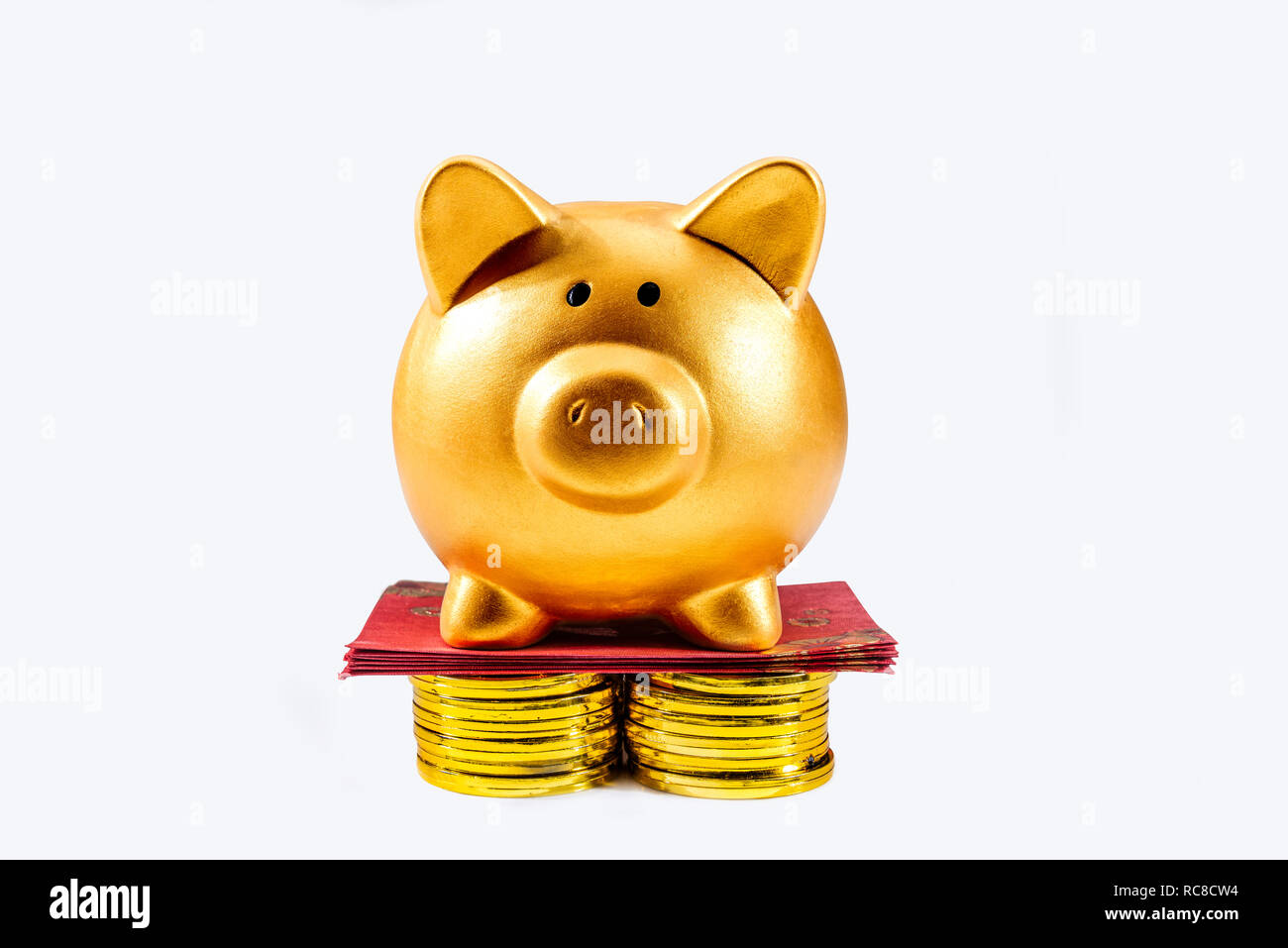 Sparschwein stehend auf den Stapel der goldenen Münze und roten Briefumschläge auf weißem Hintergrund. Das chinesische Neujahr. Jahr der Erde Schwein Stockfoto