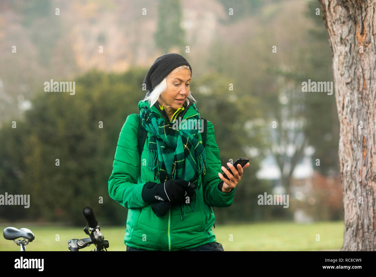 Reife Frau mit Smartphone in Park Stockfoto