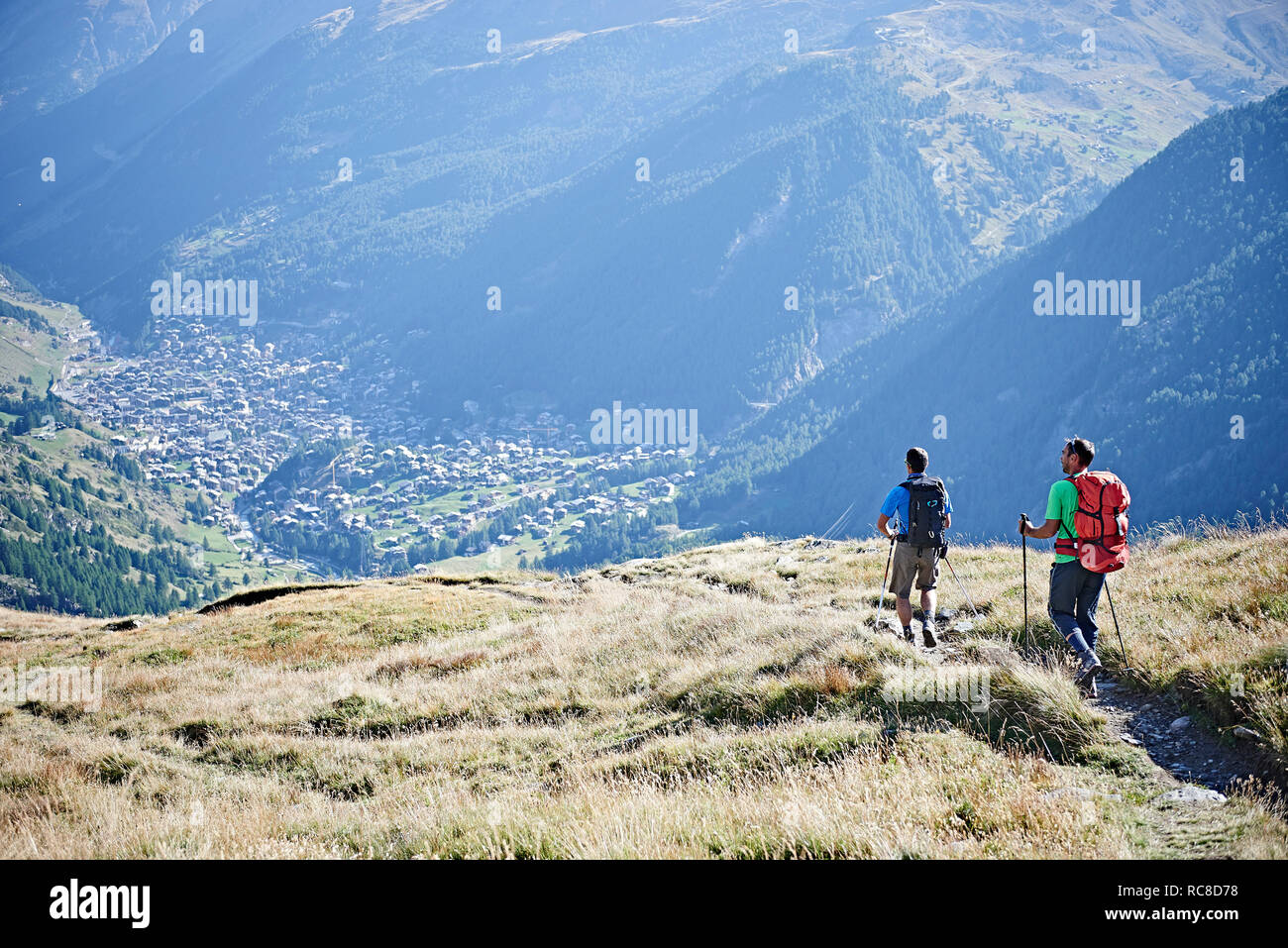 Wanderer auf grasigen Felsen mit Blick auf das Tal, Mont Cervin, Matterhorn, Wallis, Schweiz Stockfoto