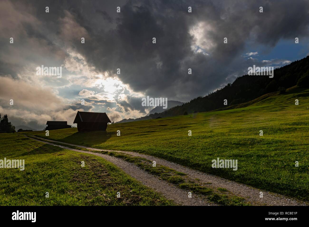 Kleine Hütte auf der Bergwiese mit Pfad und dramatische Wolken Himmel, Gerold, Mittenwald, Bayern, Deutschland Stockfoto