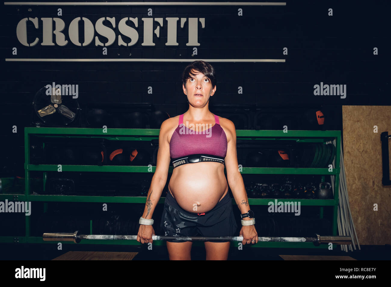 Schwangere Frau mit Bar Bell in der Turnhalle Stockfoto