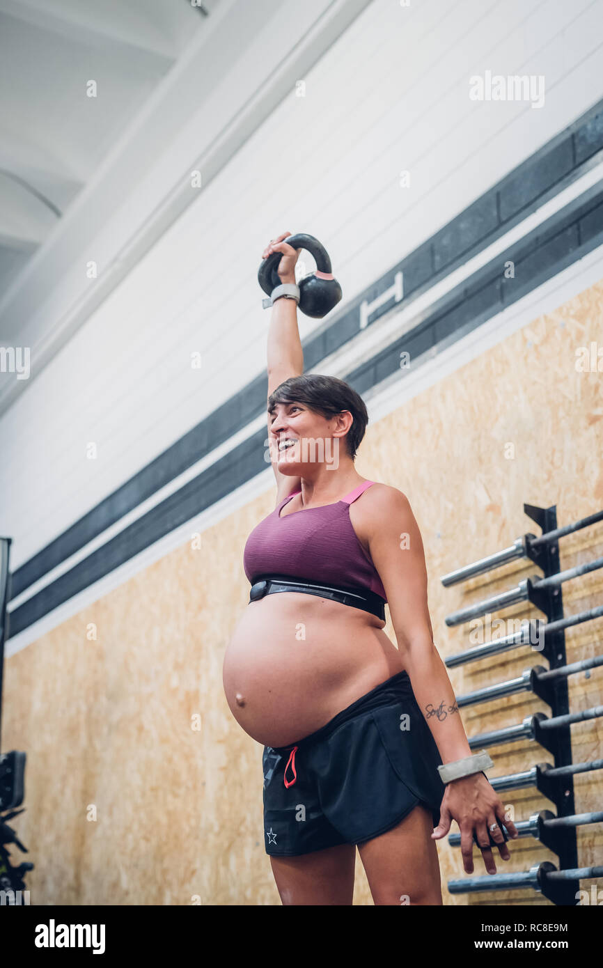 Schwangere Frau mit kettlebell in der Turnhalle Stockfoto