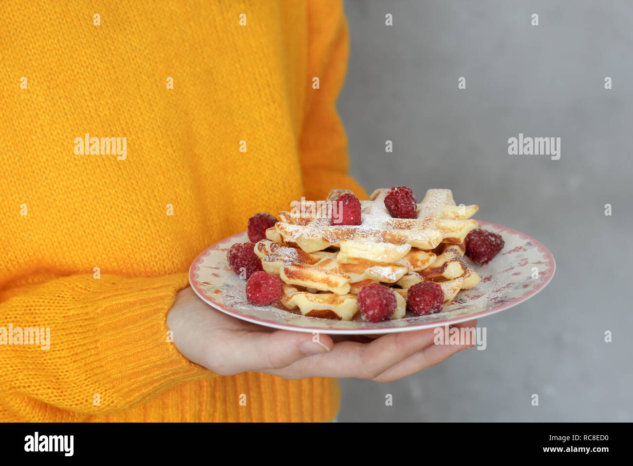 Frisch gebackene Waffeln mit Himbeeren in das Mädchen Hände Stockfoto