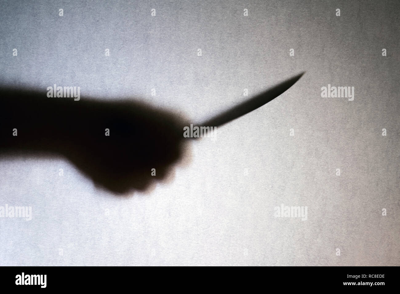 Großes Messer in Räuber hand Silhouette auf grauem Hintergrund. Mord, Raub, Verbrechen Stockfoto