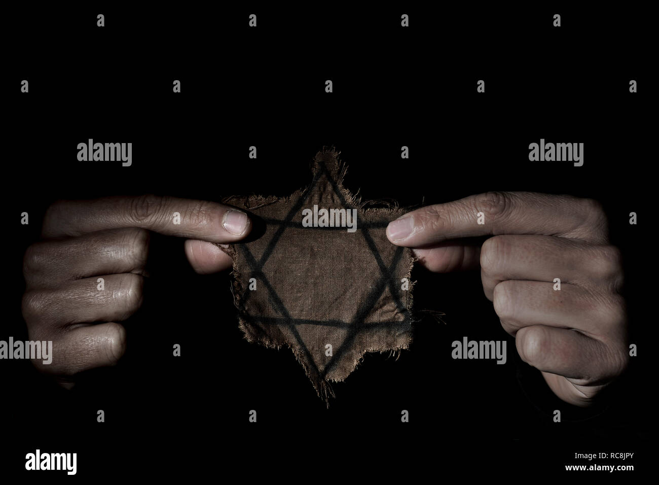 Nahaufnahme einer zerfetzten Jüdischen Abzeichen in den Händen eines Mannes, der mit einer dramatischen Effekt Stockfoto