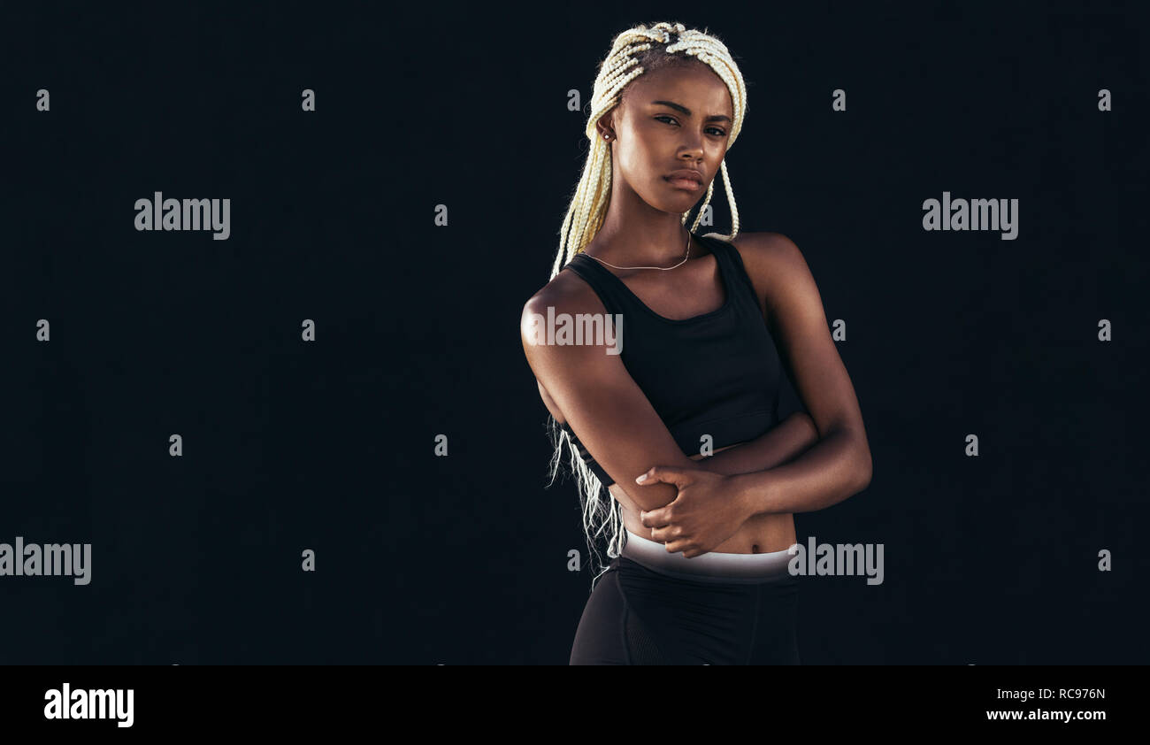 Porträt einer Athletin, die mit gefalteten Armen steht. Fitness-Frau in Trainingskleidung. Stockfoto