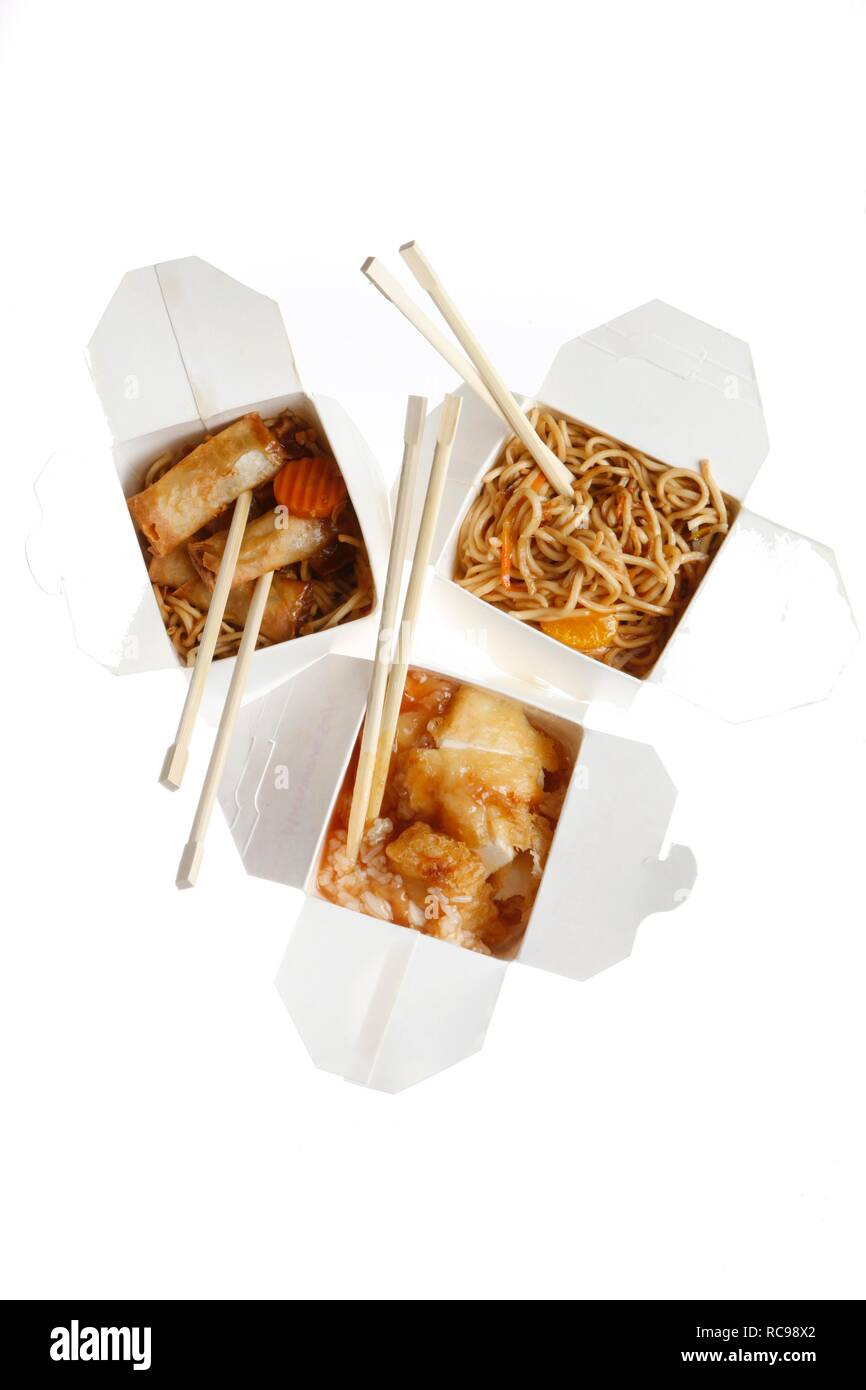 Fast food, verschiedene asiatische Gerichte, Nudeln, Frühlingsrollen und süß und sauer Huhn auf Reis, verpackt, mit Stäbchen Stockfoto