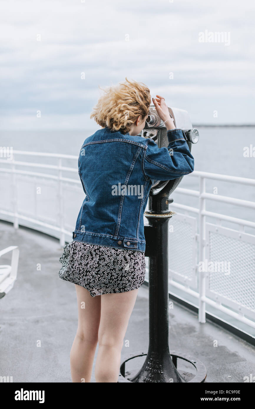 Junge Frau mit Blick auf das Meer durch Münzeinwurf Fernglas, Menemsha, Martha's Vineyard, Massachusetts, USA Stockfoto