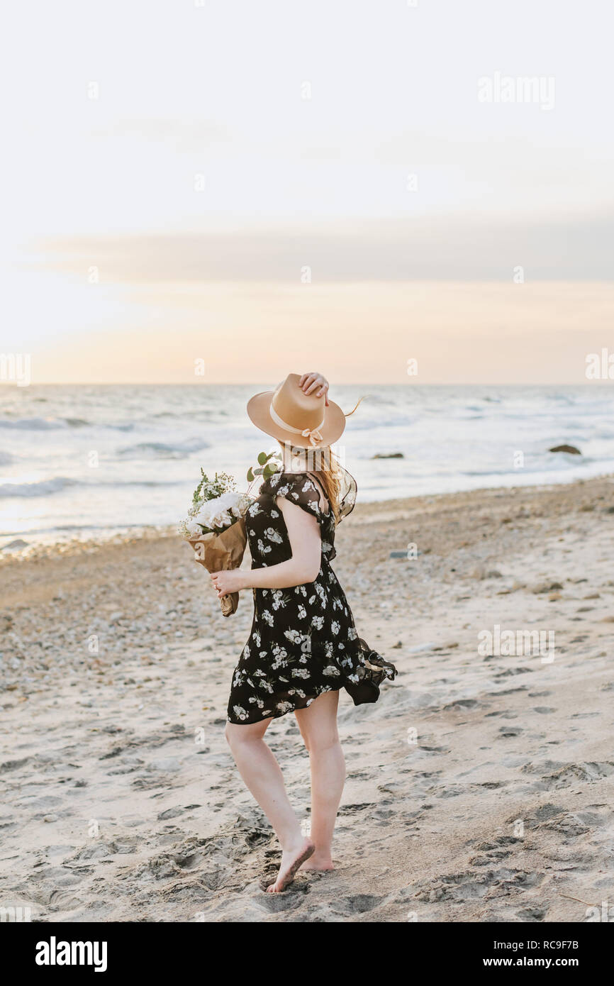 Junge Frau mit Blumen an den windigen Strand, Menemsha, Martha's Vineyard, Massachusetts, USA Stockfoto