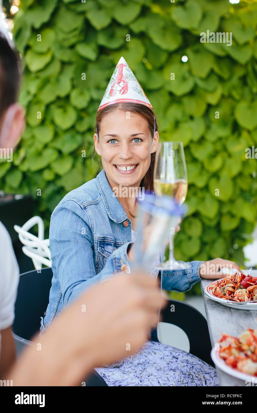 Junge Frau und Mitte der erwachsene Mann am Tisch sitzen mit Champagne flutes Stockfoto