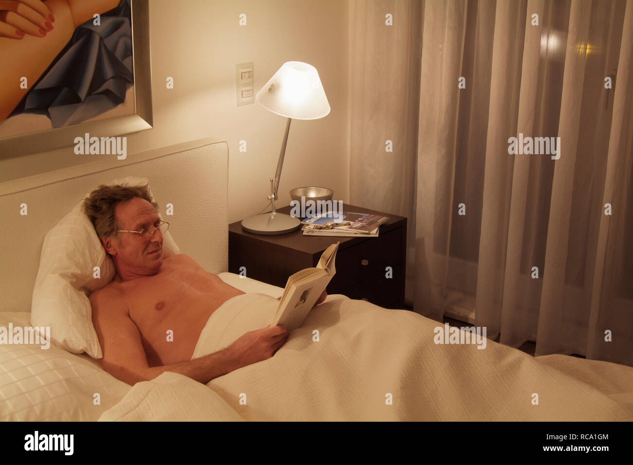 Mann mittleren Ändert liest ein Buch im Bett | mittleren Alters, der Mensch ist ein Buch lesen im Bett Stockfoto