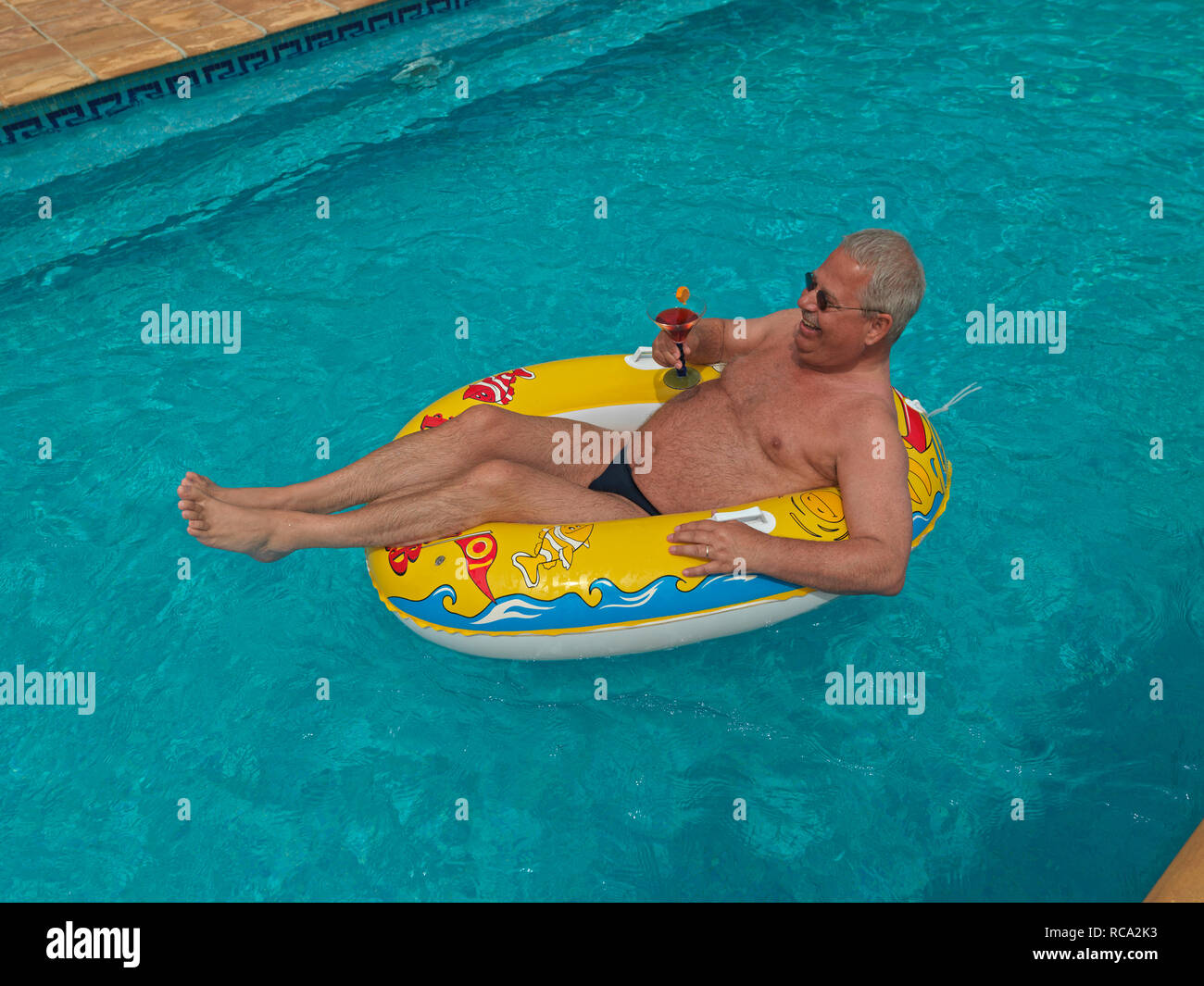 Älterer Mann genießt das Leben im kleinen Schlauchboot im Schwimmbad | älterer Mann mit einem Schlauchboot in der Swimming-pool Stockfoto