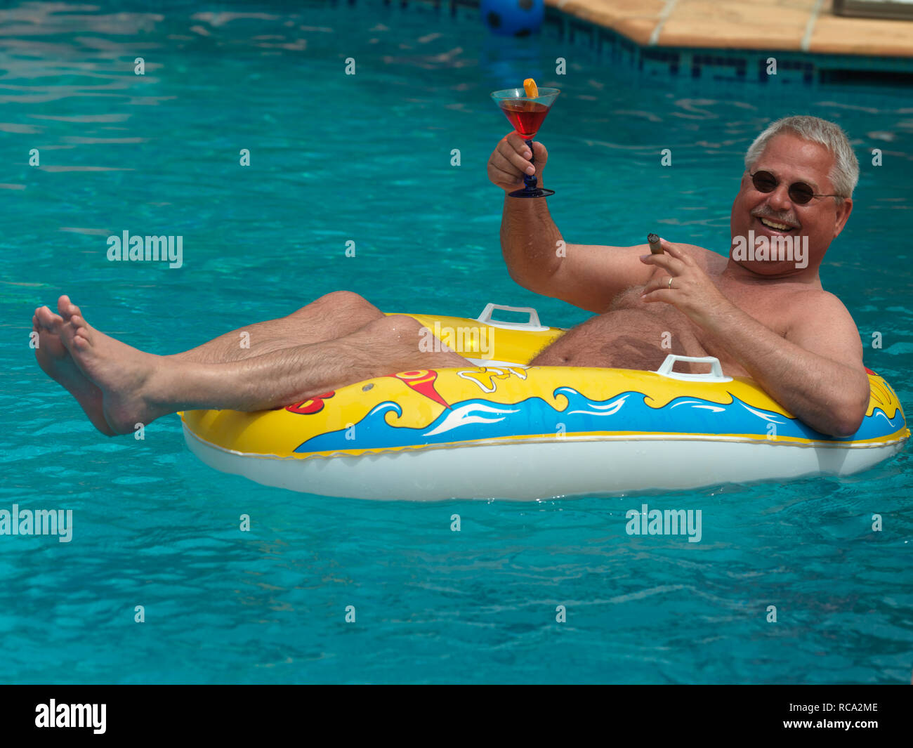 Älterer Mann genießt das Leben im kleinen Schlauchboot im Schwimmbad | älterer Mann mit einem Schlauchboot in der Swimming-pool Stockfoto