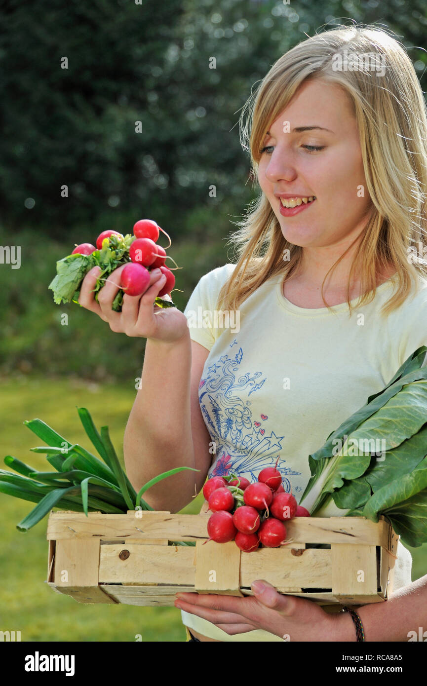 Junge Frau mit Gemüsekorb im Arm - junges Gemüse | Junge junge Frauen mit Gemüse Warenkorb Stockfoto