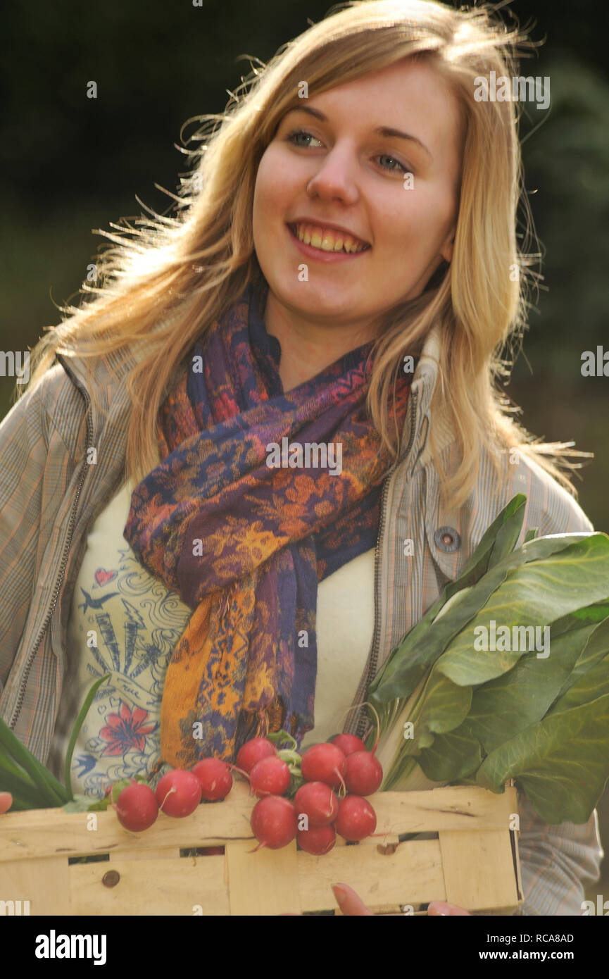 Junge Frau mit Gemüsekorb im Arm - junges Gemüse | Junge junge Frauen mit Gemüse Warenkorb Stockfoto
