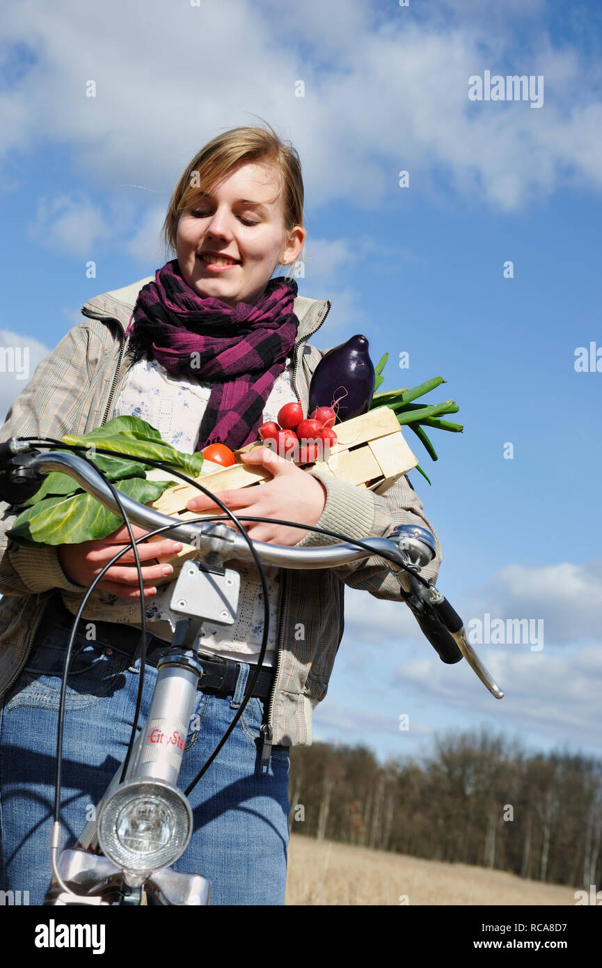 Junge Frau mit Fahhrad und Gemüsekorb - junges Gemüse | junge Frauen mit ihrem Fahrrad und Gemüse Warenkorb Stockfoto