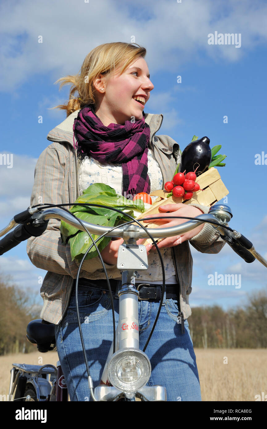 Junge Frau mit Fahhrad und Gemüsekorb - junges Gemüse | junge Frauen mit ihrem Fahrrad und Gemüse Warenkorb Stockfoto