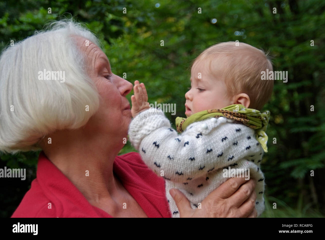 Oma hat Enkelkind im Arm | Großmutter trägt ihre Enkelin auf dem Arm Stockfoto