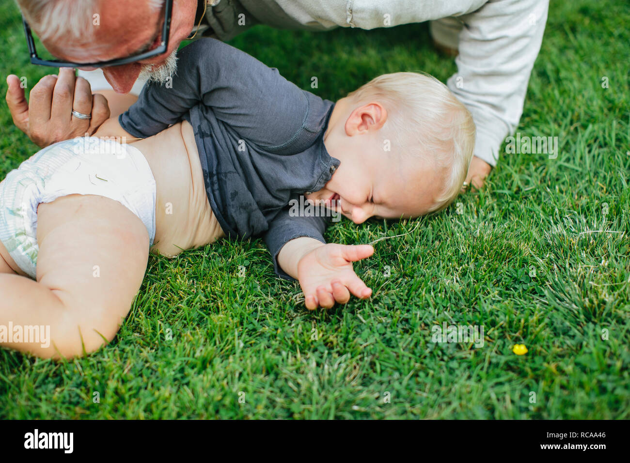 Großvater mit Enkel auf Rasen Stockfoto