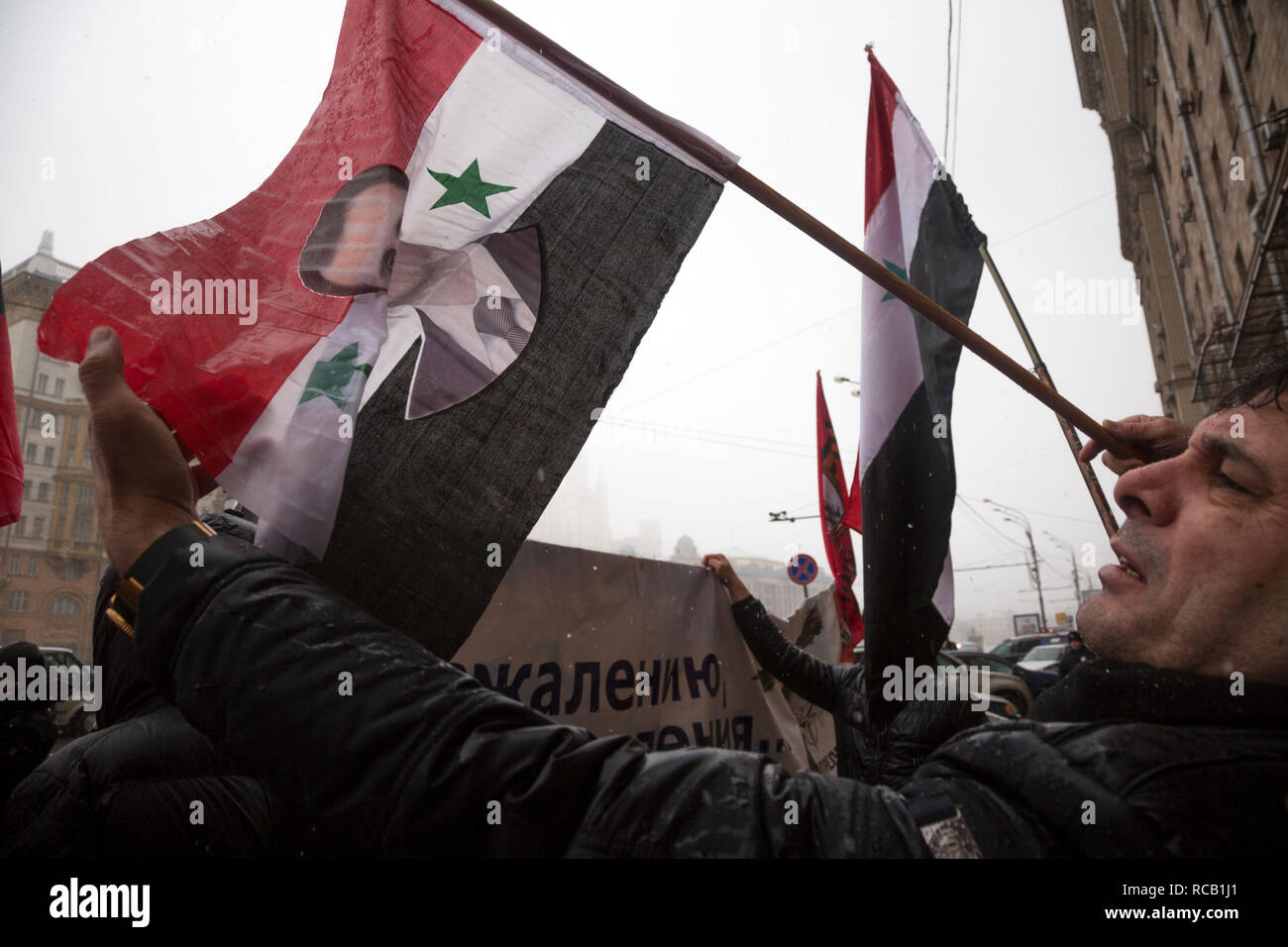 Syrische Flüchtlinge Holding eine syrische Flagge mit einem Porträt von Präsident Bashar al-Assad, der vor der US-Botschaft im Zentrum von Moskau, Russland Stockfoto