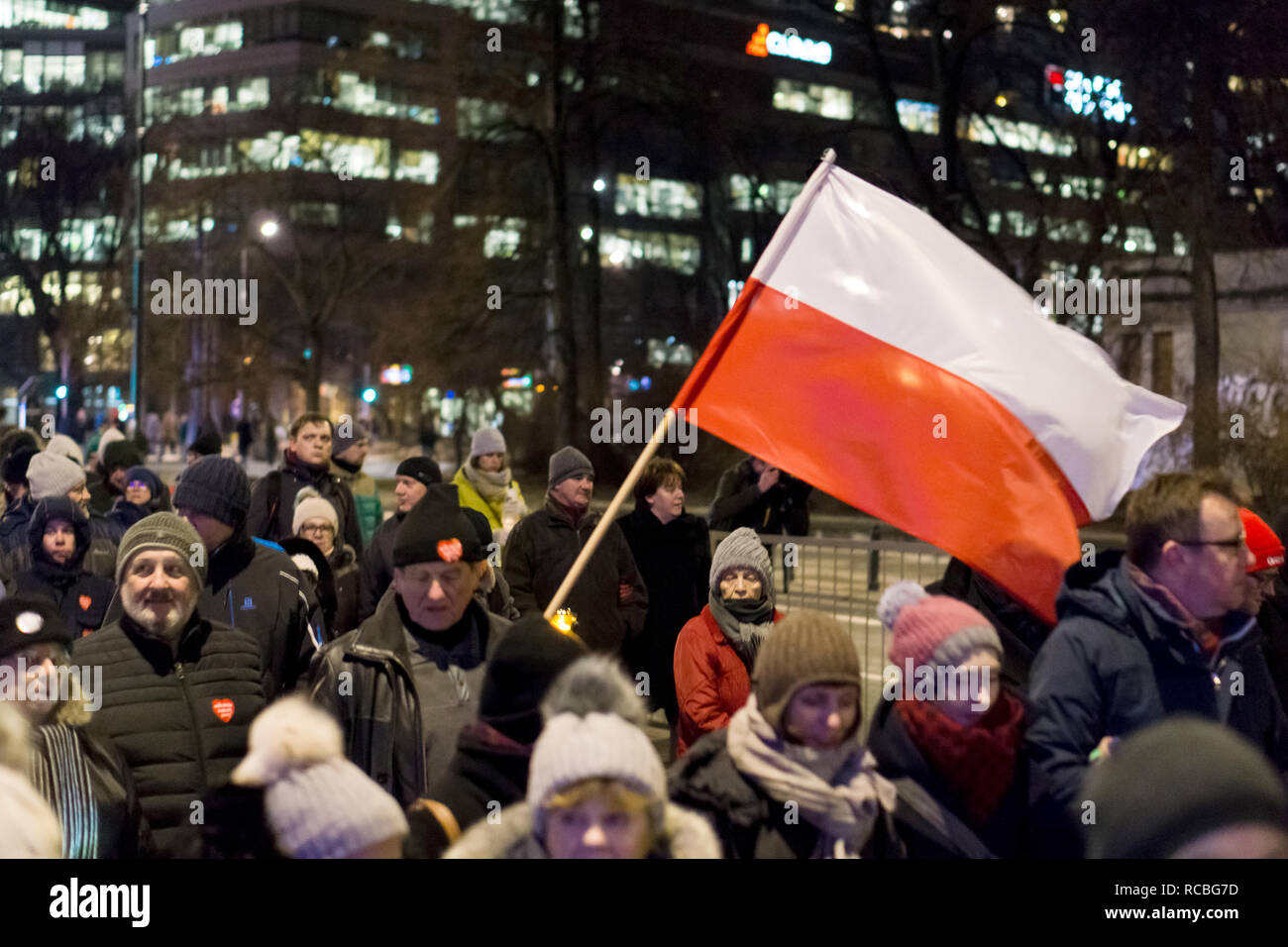 Polen, Warschau. 14. Januar 2019: Ein Mann hält während einer stillen Gedenkfeier eine polnische Flagge hoch, um ihre Trauer nach dem tragischen Tod des Danziger Bürgermeisters Pawel Adamowicz zu gedenken. Stockfoto