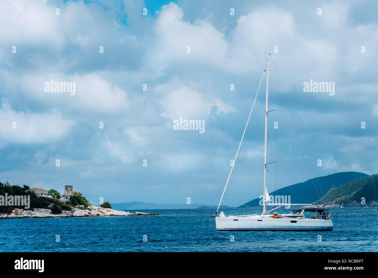 Sommer Landschaft von port Fiskardo. Weiße Segel Yacht in einer herrlichen ruhigen Bucht gegenüber von felsigen Küste. Malerische outdoor Szene der Insel Kefalonia, Griechenland, Europa. Reisen Ferienhäuser Konzept Stockfoto