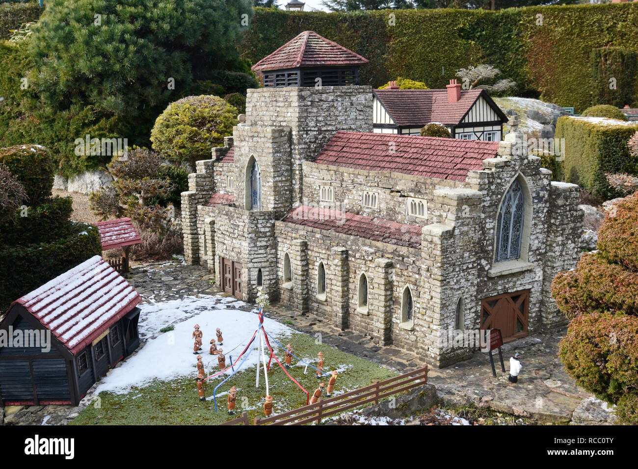 Kirche im Bekonscot Model Village, wobei Brownies auf dem Rasen Maypole spielt. Beaconsfield, Buckinghamshire, Großbritannien. Im Winter Schnee. Stockfoto
