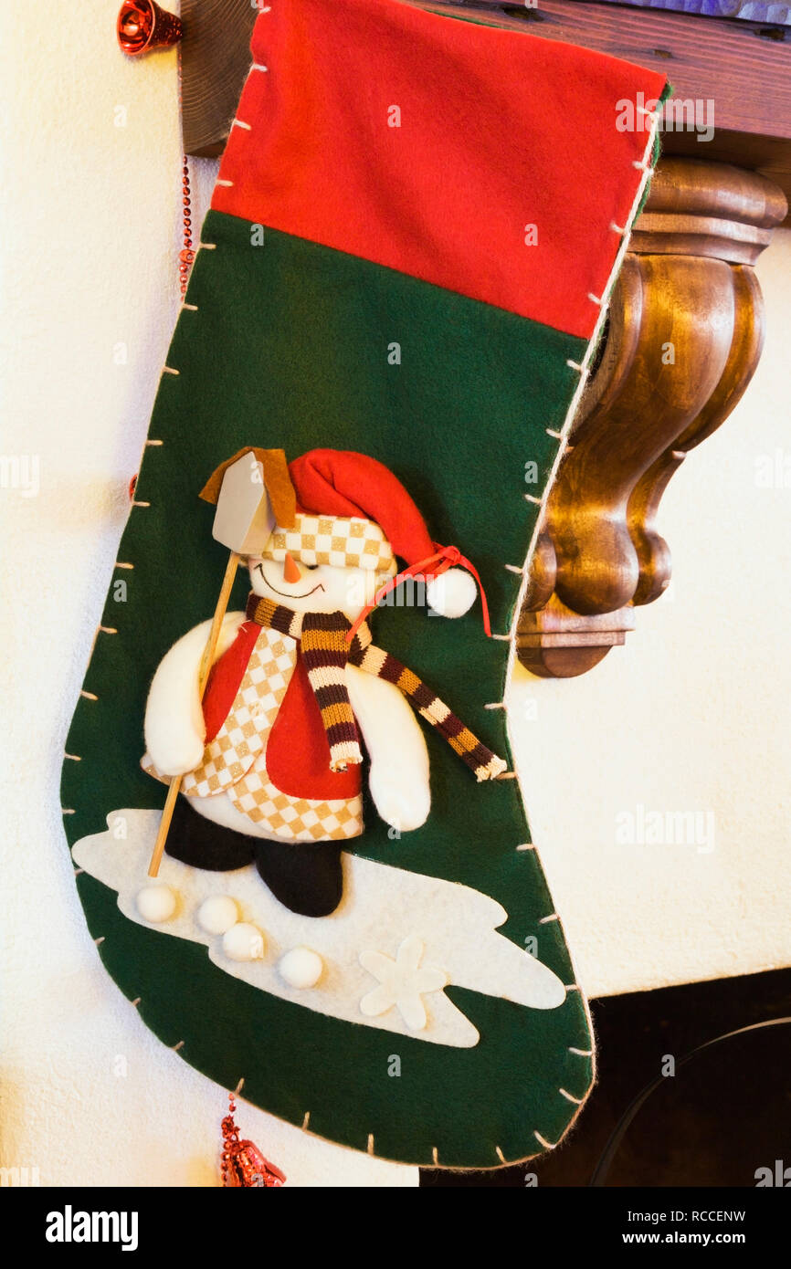 Grüne und rote Weihnachtsstrumpf mit Schneemann auf einem Kamin Mantel in einem alten Haus hing eingerichtet Stockfoto