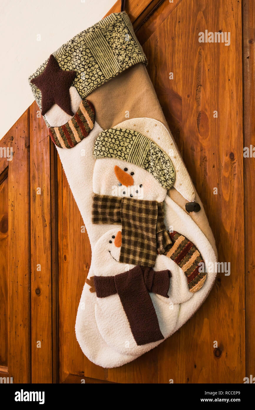 Weiß und Beige Weihnachtsstrumpf mit Schneemann auf der Seite einer Holz hing dekoriert holzgetäfelte Treppe innerhalb eines alten Home Stockfoto