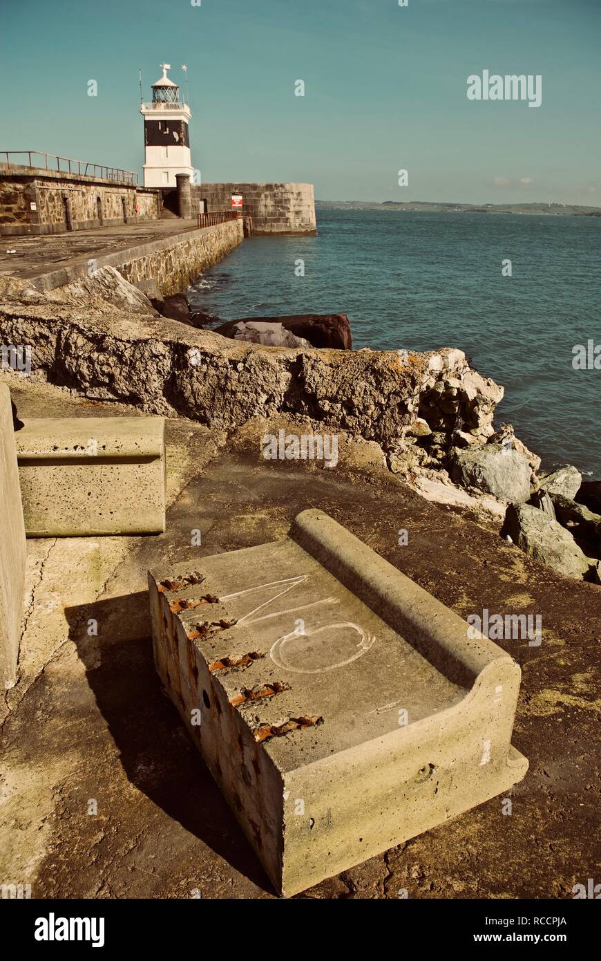 Nicht auf einem Betonklotz auf dem Holyhead Wellenbrecher Wellenbrecher gemalt mit dem Leuchtturm im Hintergrund, Holyhead, Anglesey, North Wales, UK Stockfoto